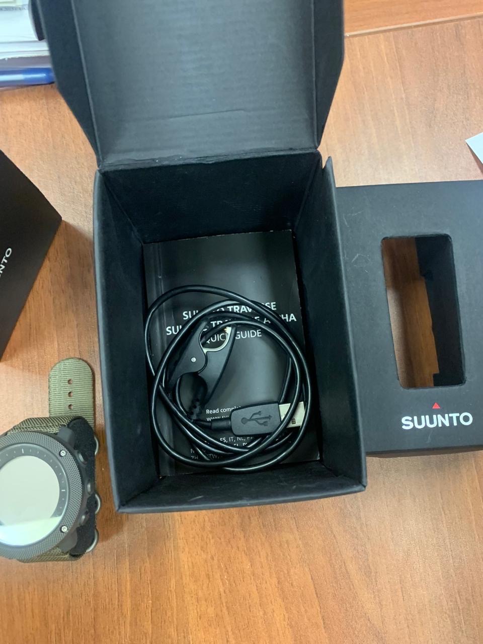 Наручные часы «Suunto» в металлическом корпусе серого цвета с коричневым ремешком, с надписями «SUUNTO TRAVERSE ALPHA Model OW151 1628103565 MSIP-CMI-asK-23922», с инструкцией, гарантией, зарядным кабелем, в черной коробке